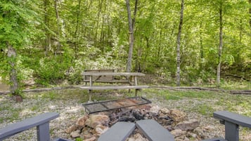 Zona de picnic con un banco de madera y un hogar para fuego rodeado de rocas.