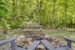 Un espace de pique-nique équipé d’un banc en bois et d’un foyer entouré de rochers.