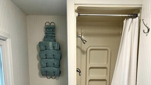 A bathroom with a toilet, a sink, a shower with a curtain, and a towel rack with folded towels.