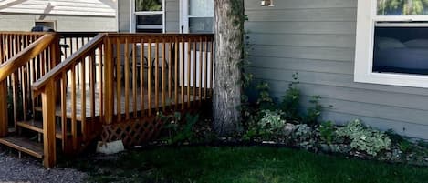 A single-story house with a wooden deck, a front door, and a small window.
