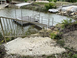 A concrete staircase leading to a dock over water, surrounded by natural vegetation. - Family Style Glamping in Pet-Friendly Rental at Lake Godstone, Texas (Graford)