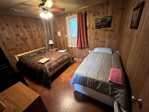 A room with two beds, a ceiling fan, a window with curtains, and a wooden floor. - Family Style Glamping in Pet-Friendly Rental at Lake Godstone, Texas (Graford)