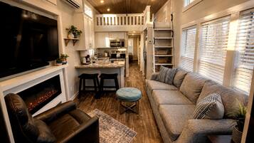 A compact living space with a television, seating area, kitchenette, and a fireplace.
