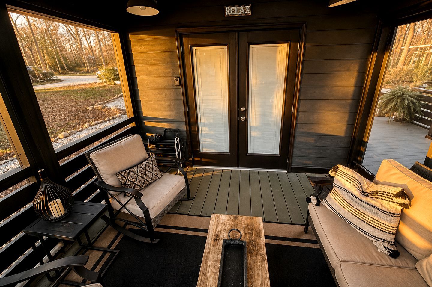 A porch with a rocking chair, a sofa, and a small table.