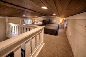 A bedroom with a bed, bedside tables, a nightstand, a window, and a wooden ceiling. - Chic Tiny Cabin with Jacuzzi, Screened Porch and Grill in Tennessee (Tracy City)