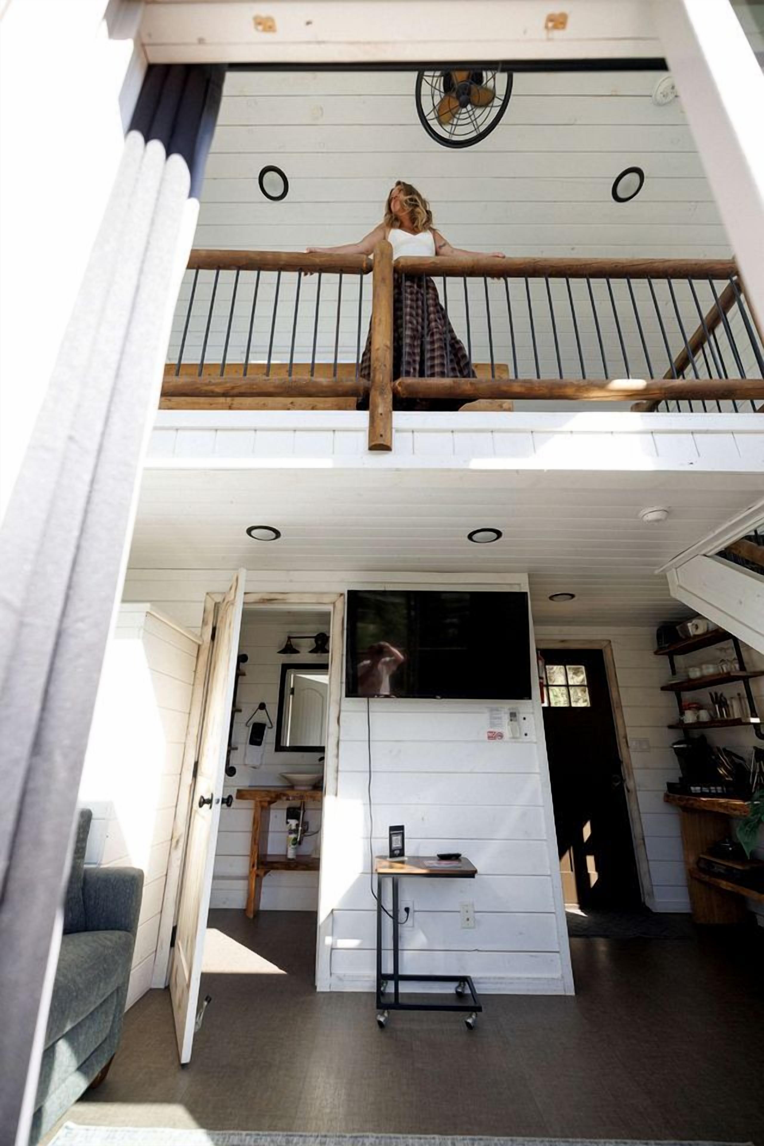 Un bâtiment à deux étages doté d’un balcon, d’un coin cuisine et d’une petite table avec une chaise.