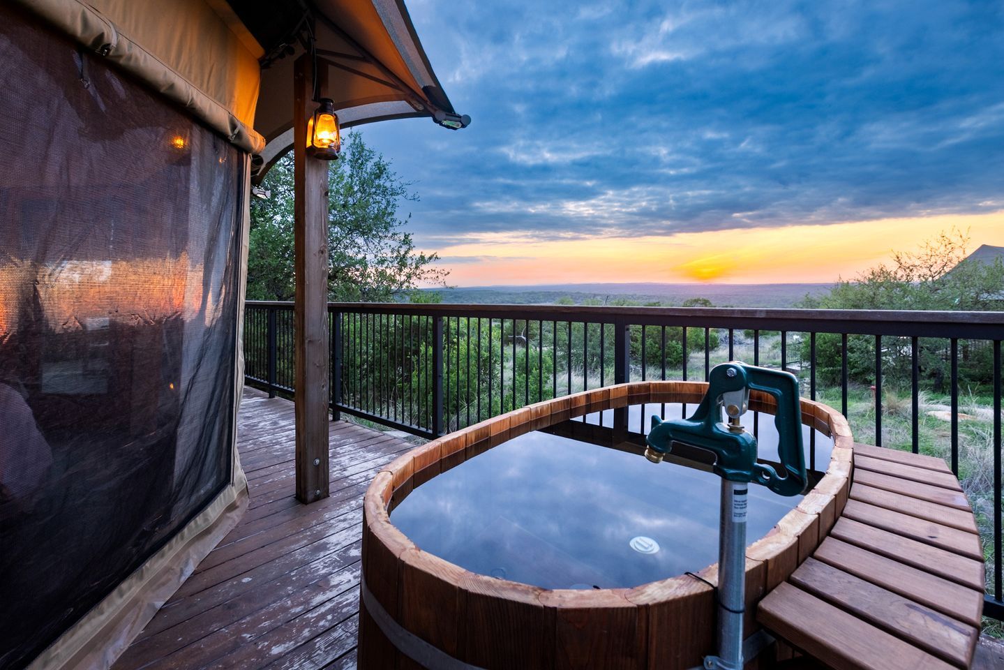 Un bain à remous sur une terrasse en bois, avec vue sur le coucher de soleil.