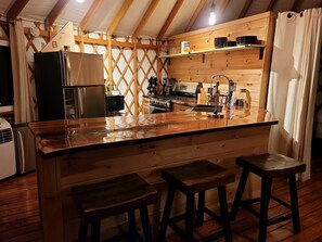 Eine Küche mit Holzbalken, einem Edelstahlkühlschrank, einem Herd und einer Holztresen mit Hockern.
