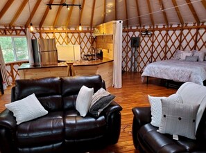 Ein gemütliches Interieur mit Ledersofa, Bett, einer kleinen Küchenzeile und einer Wand mit Holzgitter.