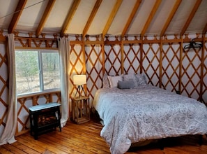 Un dormitorio con cama, mesita de noche, lámpara y ventana.