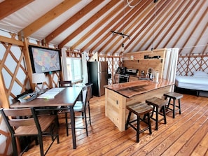 Ein gemütliches Interieur mit Holztisch, Stühlen, Küchenzeile und einem Bett.