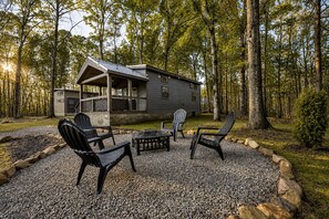 Une cabane dotée d’un porche, d’un espace extérieur aménagé pour s’asseoir et d’une zone recouverte de gravier.