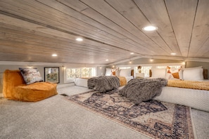 Ein geräumiges Schlafzimmer im Loft-Stil mit hohen Decken, einem großen Fenster und einer gemütlichen Sitzecke.