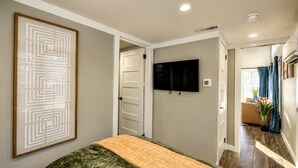 A bedroom with a bed, a TV, a door, and a hallway leading to another room. - Cozy Wooden Cabin Surrounded by Trees in Monteagle, Tennessee (Monteagle)