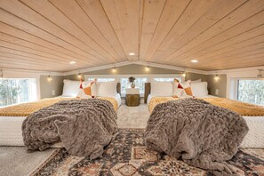 Une chambre avec deux lits, un plafond en bois et une vue sur les arbres à l’extérieur.