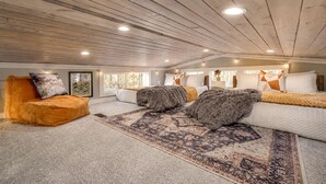 Une chambre spacieuse aménagée en loft, avec un plafond haut, une grande fenêtre et un coin salon confortable.
