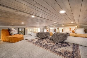 Une chambre spacieuse aménagée en loft, avec un plafond haut, une grande fenêtre et un coin salon confortable.