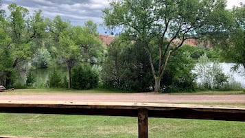 A park with a wooden deck, trees, and a lake.