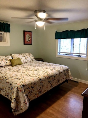 A bedroom with a bed, a ceiling fan, a window with curtains, and a wall-mounted picture. - Cozy Relaxing Cabin with Lake Views in South Dakota (Hot Springs)