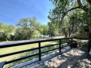 A wooden deck with a railing overlooking a grassy area with trees. - Cozy Relaxing Cabin with Lake Views in South Dakota (Hot Springs)