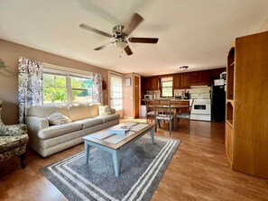 A living room with a sofa, coffee table, and a dining area with chairs and a table. - Cozy Relaxing Cabin with Lake Views in South Dakota (Hot Springs)