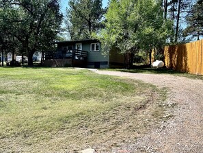 A residential property with a house, a fenced yard, and a gravel driveway. - Cozy Relaxing Cabin with Lake Views in South Dakota (Hot Springs)