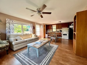 A living room with a sofa, coffee table, and a dining area with chairs and a table. - Cozy Relaxing Cabin with Lake Views in South Dakota (Hot Springs)