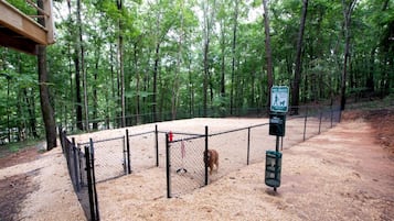A fenced outdoor area with a pet waste station, surrounded by trees.