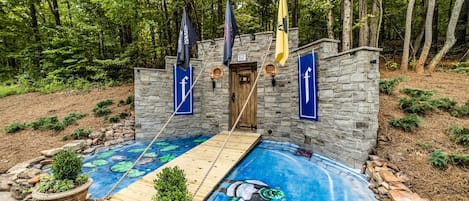 A stone building with a wooden deck and a swimming pool with a mural.