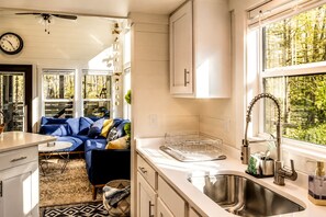 A modern kitchen with a sink, cabinets, and a window overlooking greenery. - Charming Cabin with Stunning Sights in Monteagle, Tennessee (Monteagle)