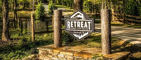 Une pancarte indiquant un centre de retraite appelé « Deer Lick Falls », situé à Hohenwald, dans le Tennessee, et entouré d’arbres et d’un mur de pierres.