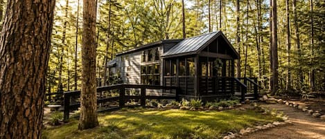 A cabin with a porch, surrounded by a forest.