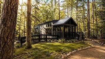 A cabin with a porch, surrounded by a forest.