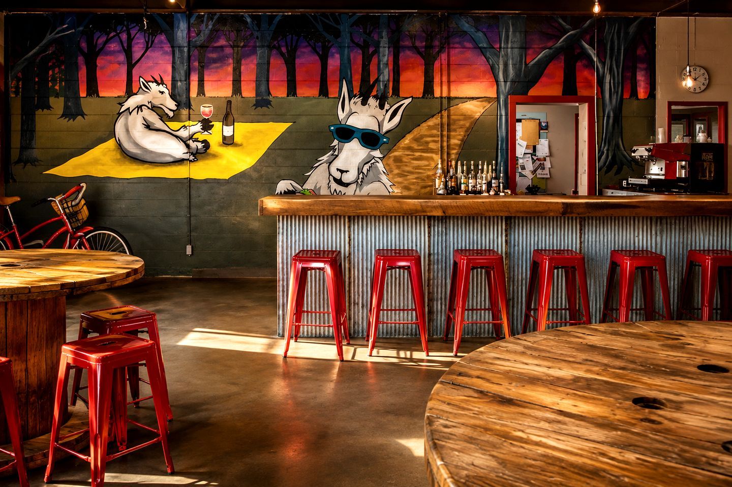 Zona de bar con un mural de lobos, taburetes rojos y una barra de madera.