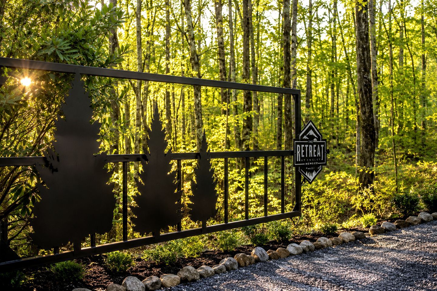 A metal gate with a retreat sign, surrounded by a forested area with trees and a gravel path.
