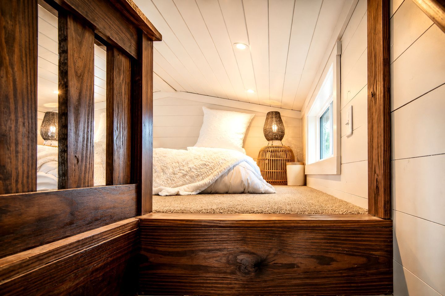 Un dormitorio con cama, ventana y suelo de madera.
