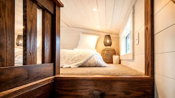 Un dormitorio con cama, ventana y suelo de madera.