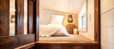 Ein Schlafzimmer mit einem Bett, einem Fenster und Holzboden.