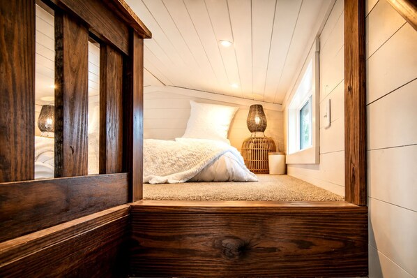 A bedroom with a bed, a window, and a wooden floor.