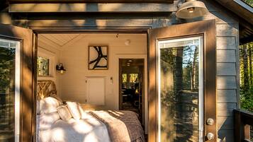 A cozy bedroom with a bed, a door leading to another room, and a window.