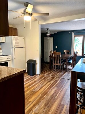 Una cocina con refrigerador, estufa y piso de madera.