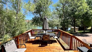 A wooden deck with a table and chairs, surrounded by a wooden railing.
