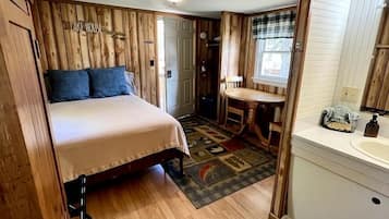 Una habitación pequeña con cama, una mesita y un lavamanos.