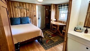 Un dormitorio con cama, una mesita y una ventana.