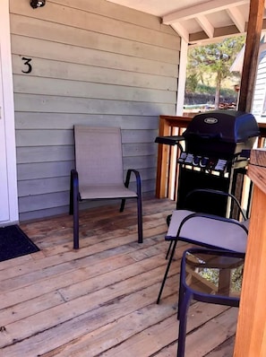 A porch with a grill, two chairs, and a number '3' on the wall.