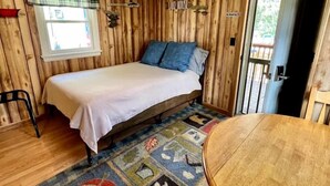 Una habitación con cama, una mesa redonda, una ventana con cortinilla escocesa y un cartel de 'No Smoking'.