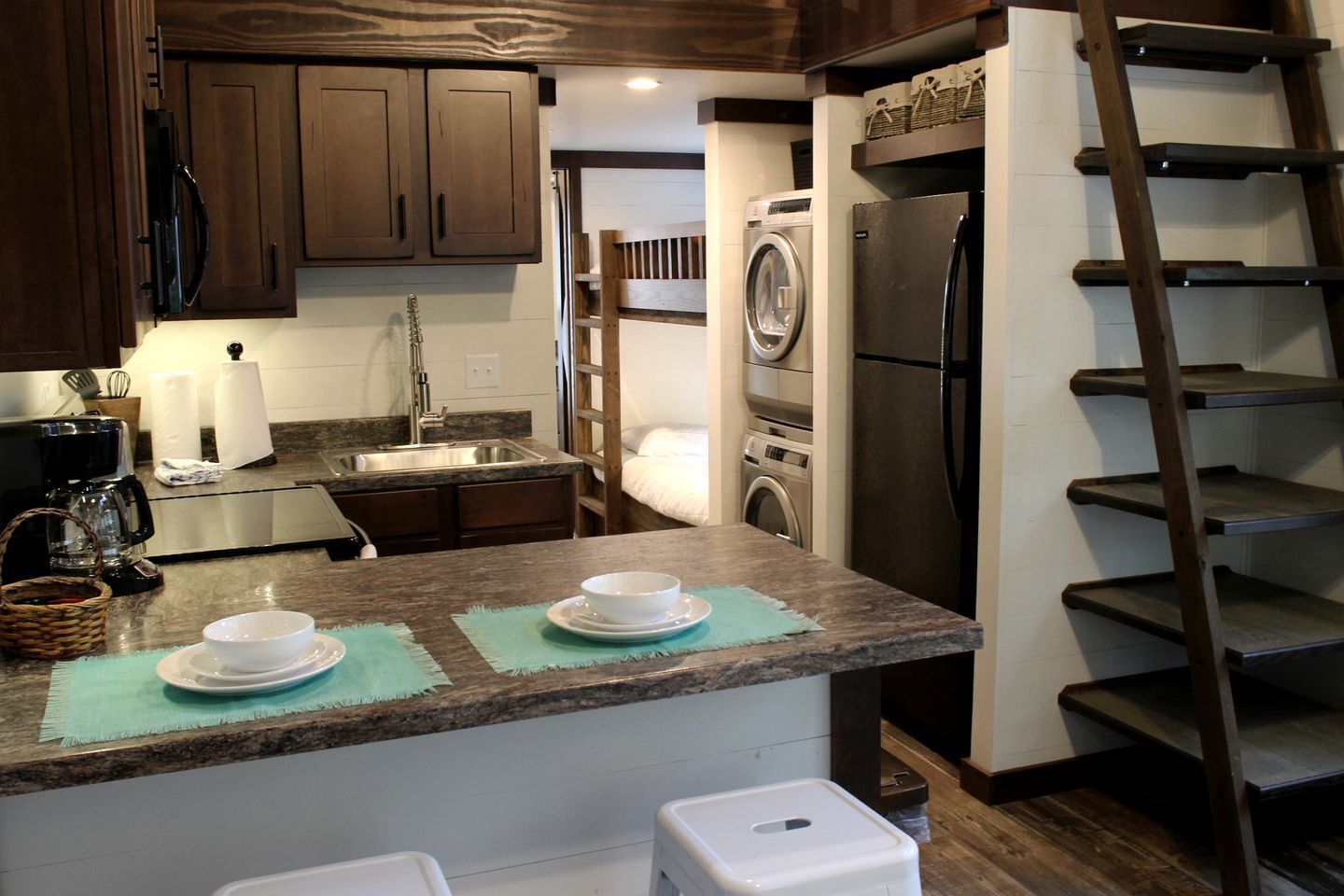 Una cocina con armarios de madera oscura, electrodomésticos de acero inoxidable, una cafetera y un lavabo.