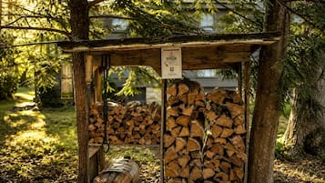 A wooden structure with a sign, surrounded by trees and a pile of logs.