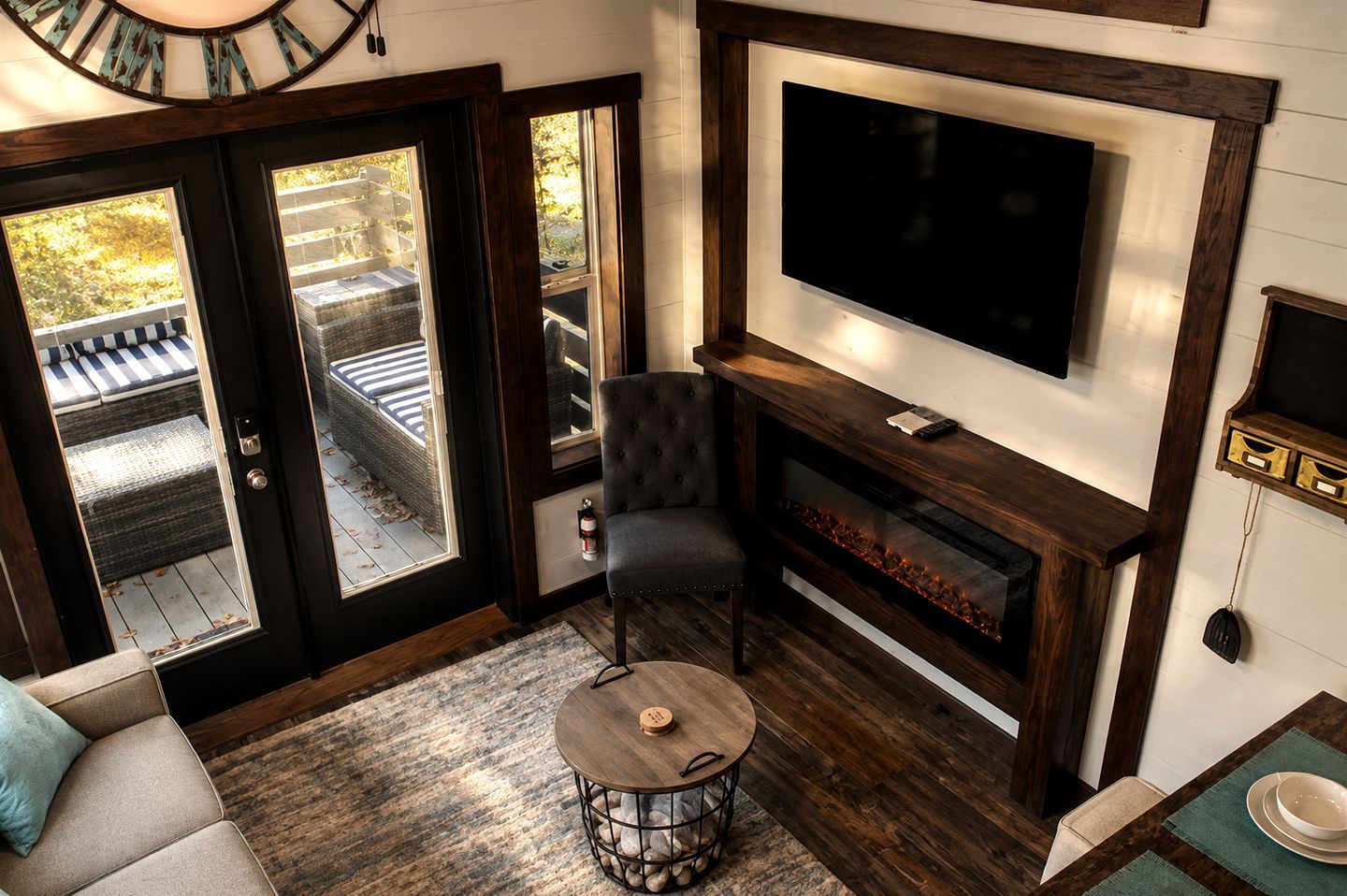 Un salon chaleureux avec une cheminée, un téléviseur fixé au-dessus, et un coin salon confortable avec un canapé et un fauteuil.