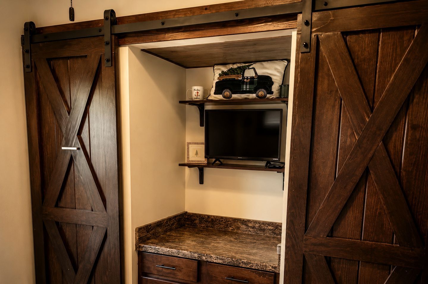 A room with a sliding barn door, a television on a shelf, and a small table with drawers.